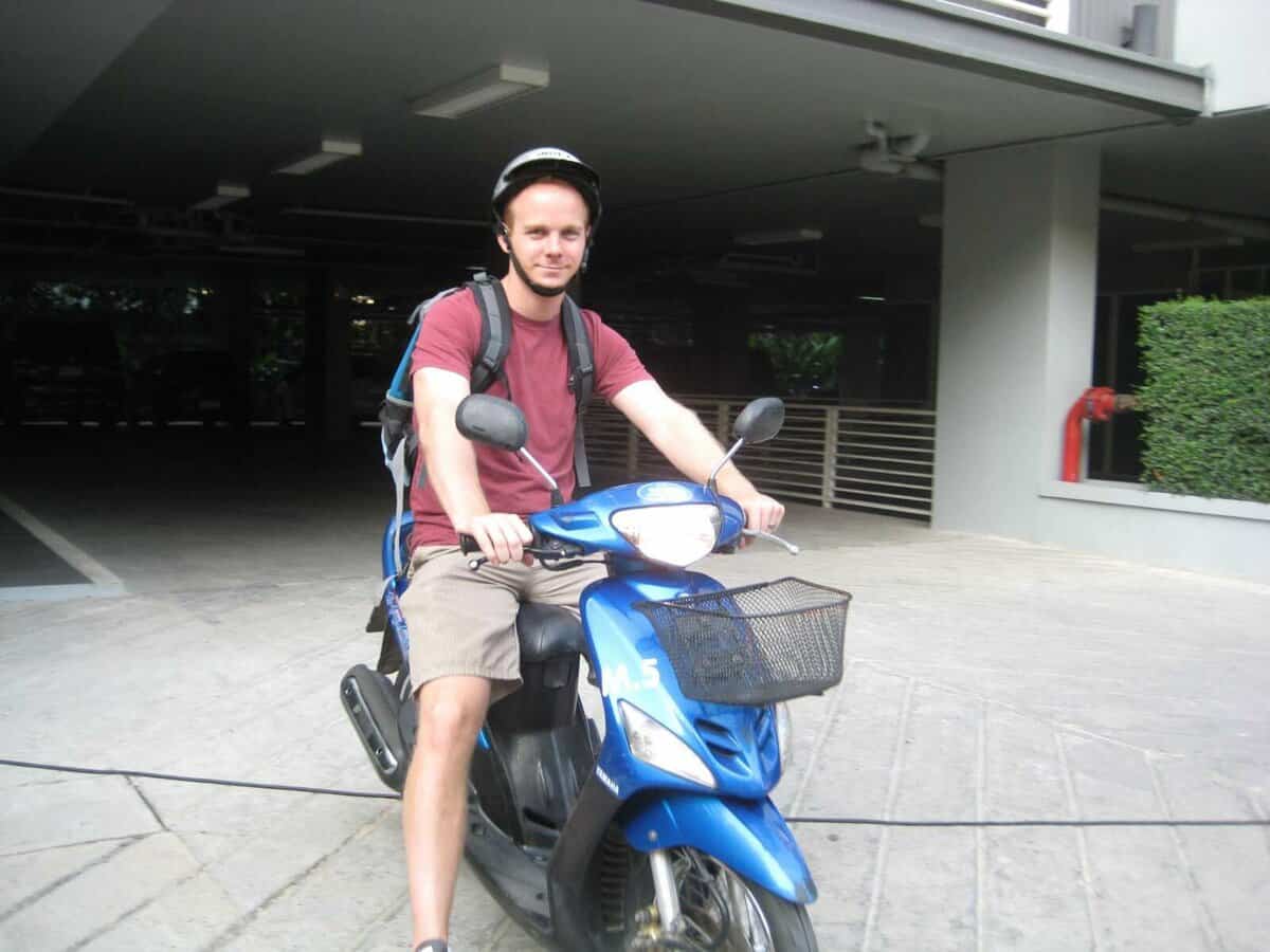 Person riding a blue scooter in Chiang Mai, Thailand.