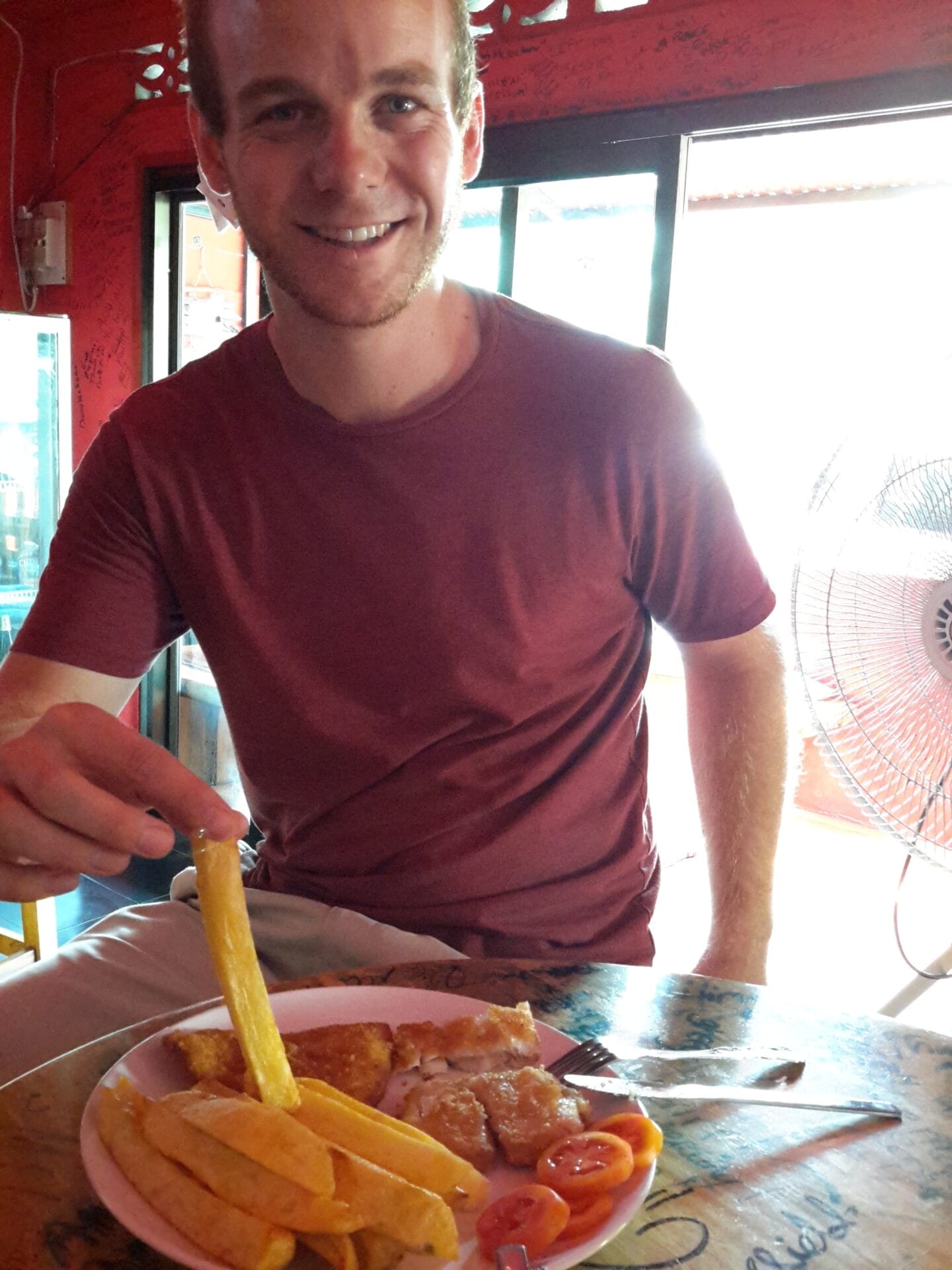 A person enjoying a plate of fish and chips at The Hub Pub in Chiang Khong, Thailand.