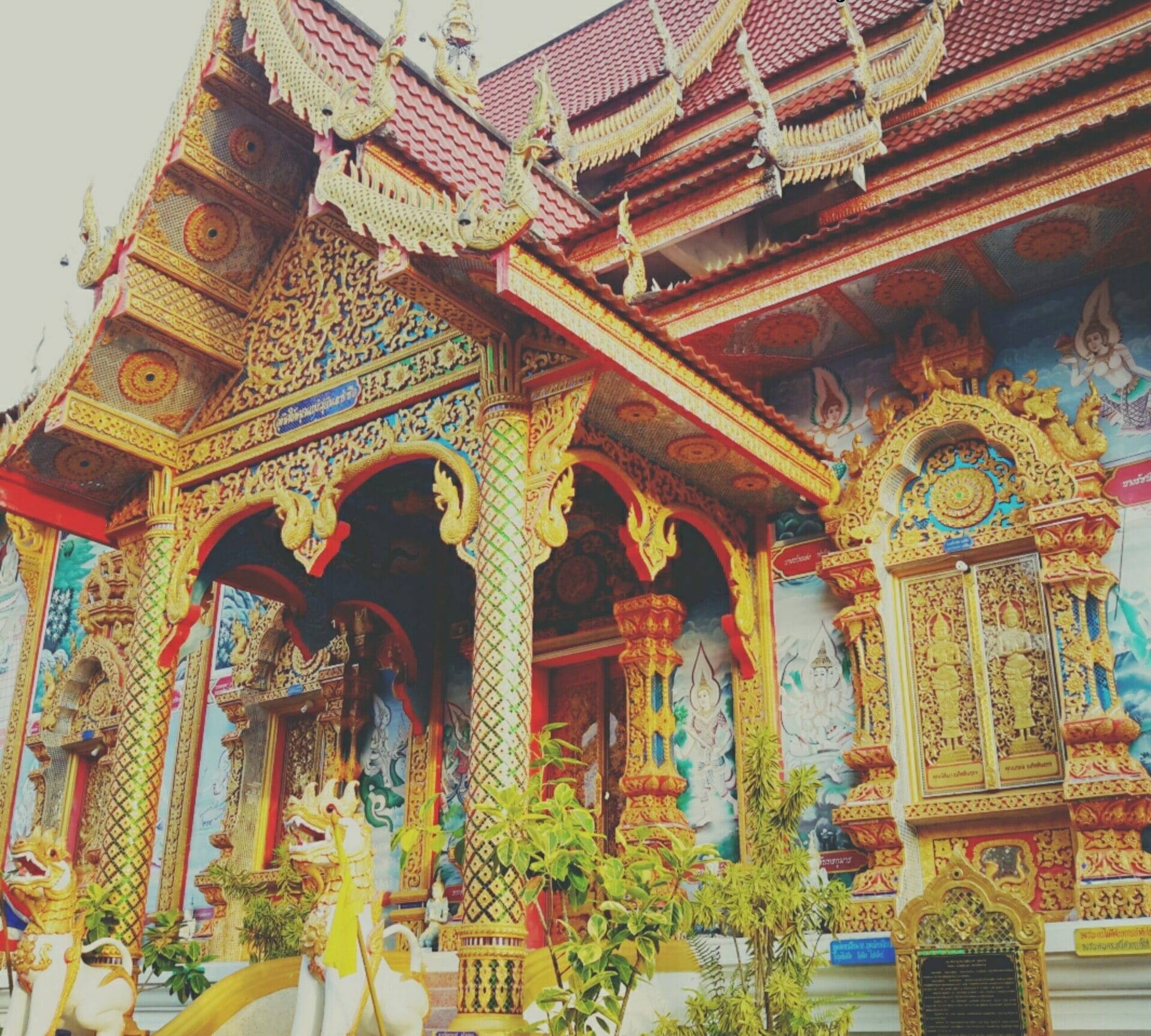 Ornately decorated temple at Wat Luang Chai Sathan in Chiang Khong, Thailand, featuring intricate gold carvings and statues.