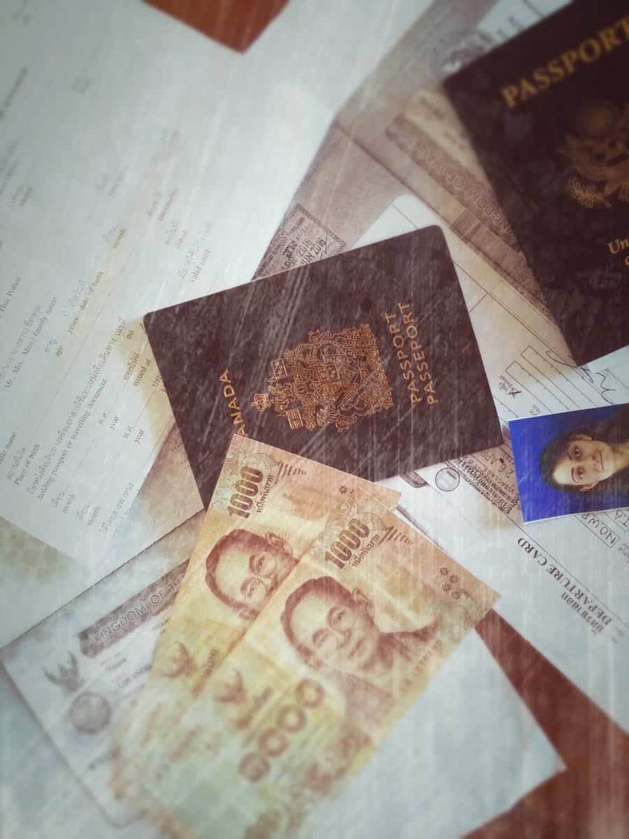 Passport, documents, and Thai currency for visa extension in Thailand.