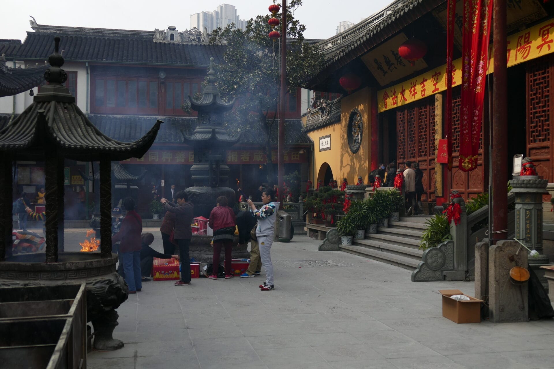 Visitors gathering and lighting incense at the Jade Buddha Temple courtyard in Shanghai, China.