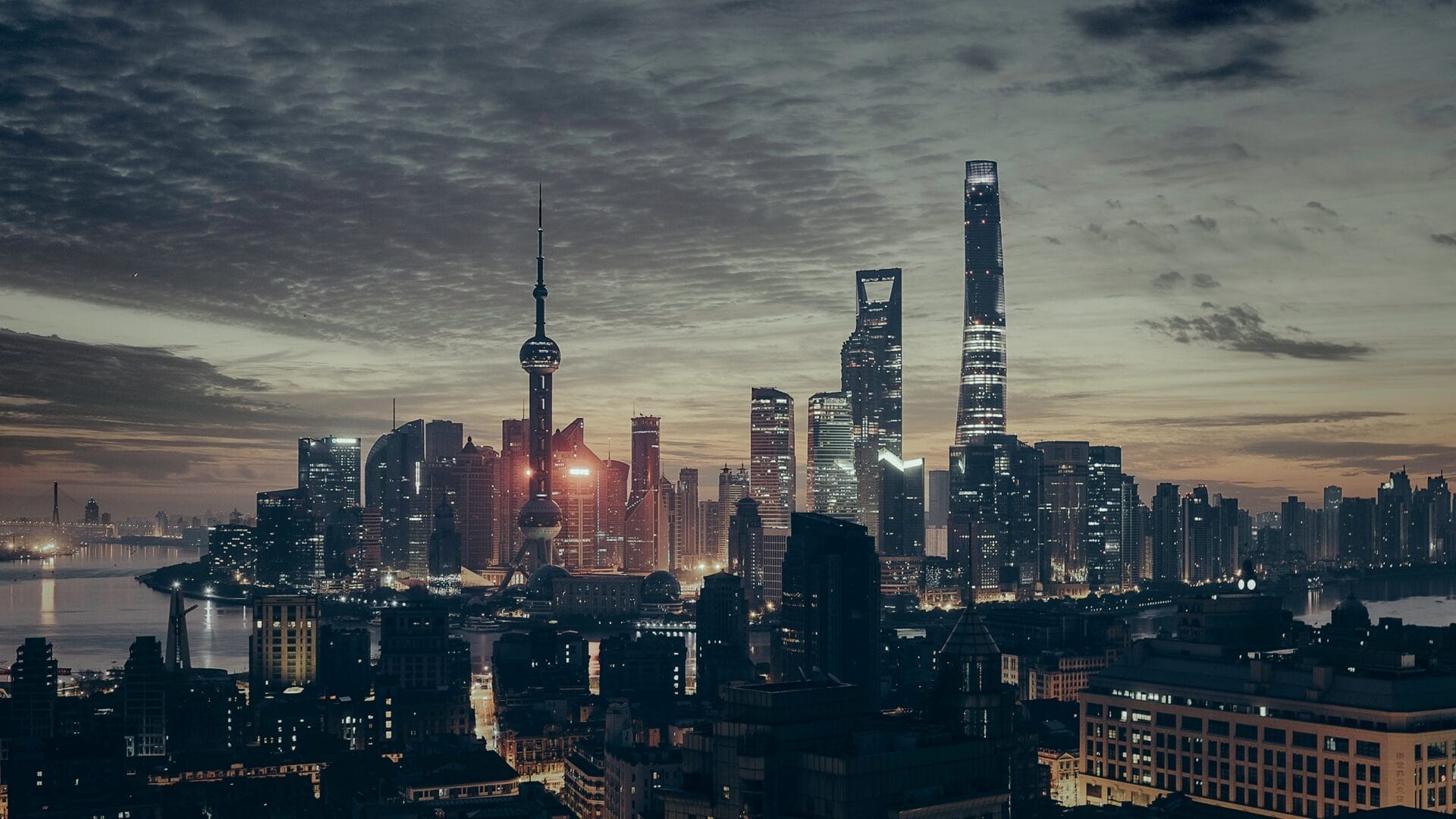 Skyline of Shanghai, China at dusk with illuminated skyscrapers.
