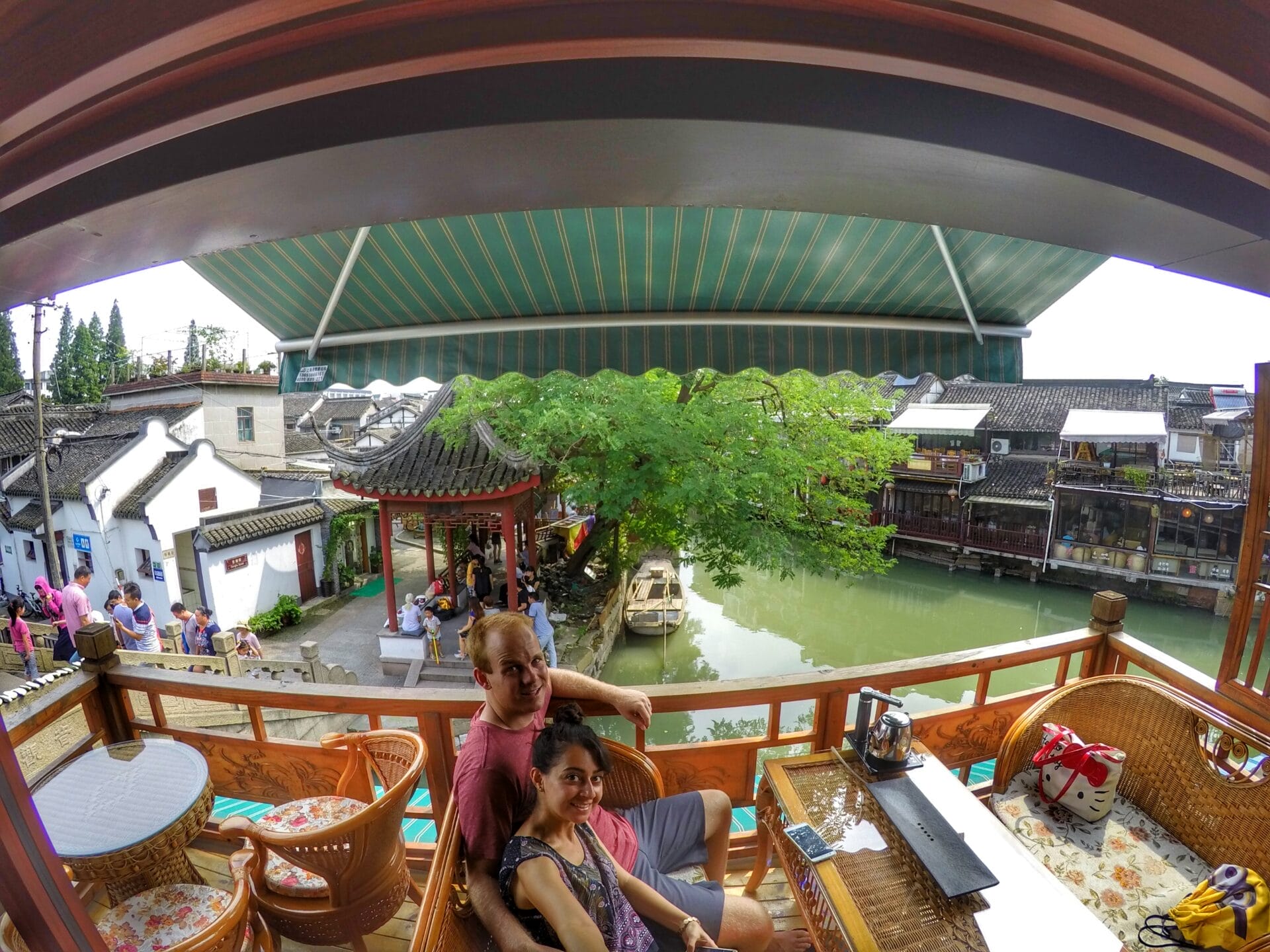 A couple sitting on a balcony overlooking a canal and traditional buildings in Zhujiajiao, Shanghai, China.