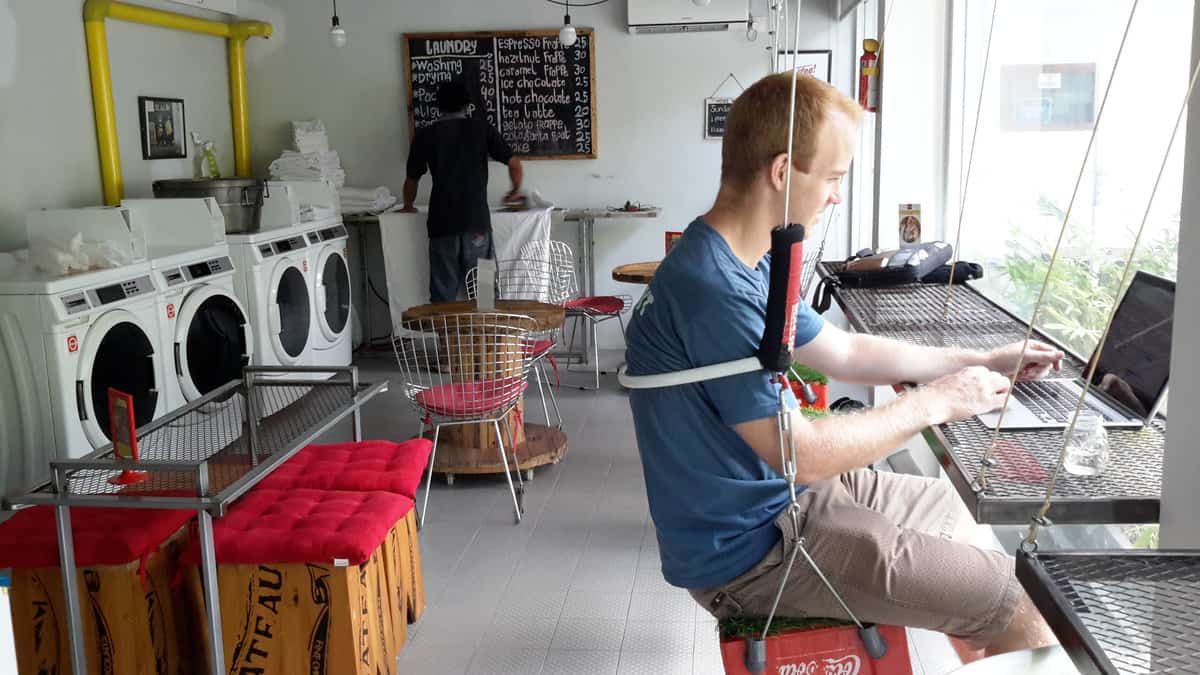 Person working on a laptop at a unique café-laundromat in Denpasar, Bali.