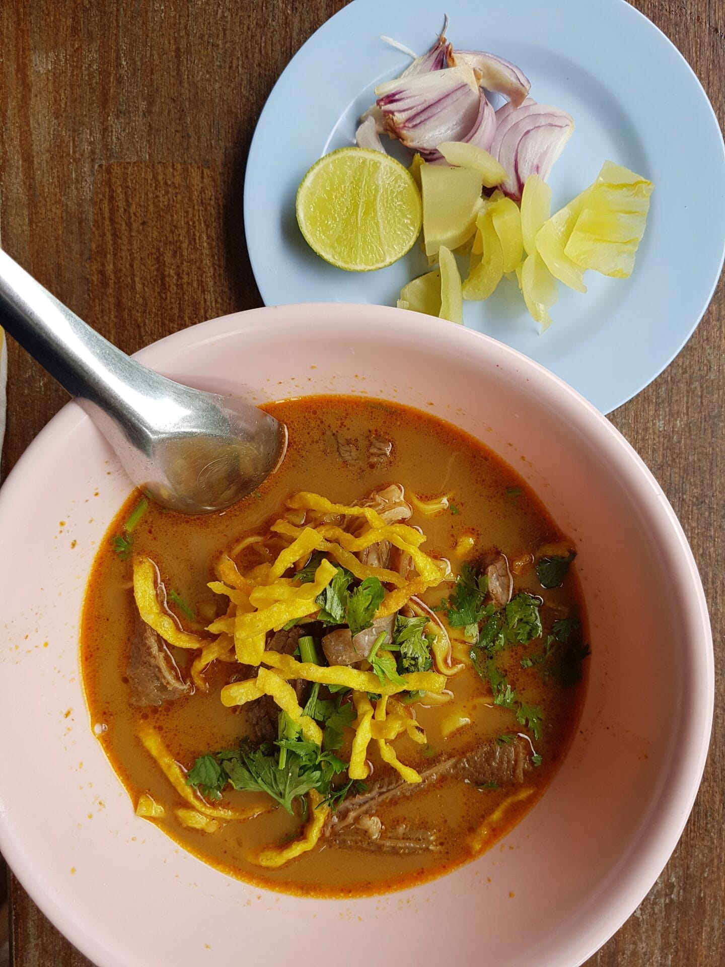 Bowl of Khao Soi with condiments in Chiang Mai, Thailand