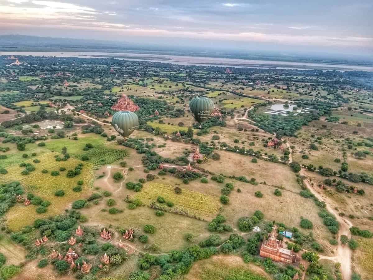 Bagan, Myanmar from above Arial view of Bagan, Myanmar featuring hot air balloons floating over a landscape dotted with ancient temples and surrounding greenery.