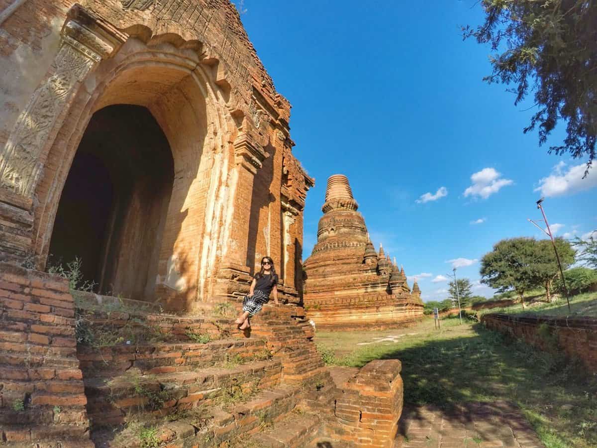 Bagan, Myanmar for first timers Ancient temple ruins in Bagan, Myanmar, with a person sitting on stone steps in the foreground.