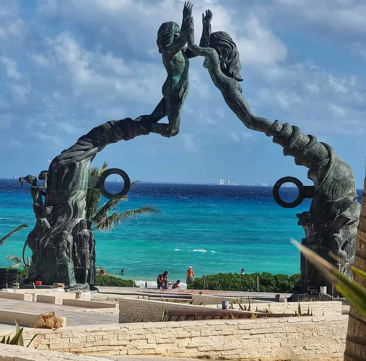 The Portal Maya statue in Founders Park, Playa del Carmen, Quintana Roo, Mexico, with a backdrop of the Caribbean Sea.
