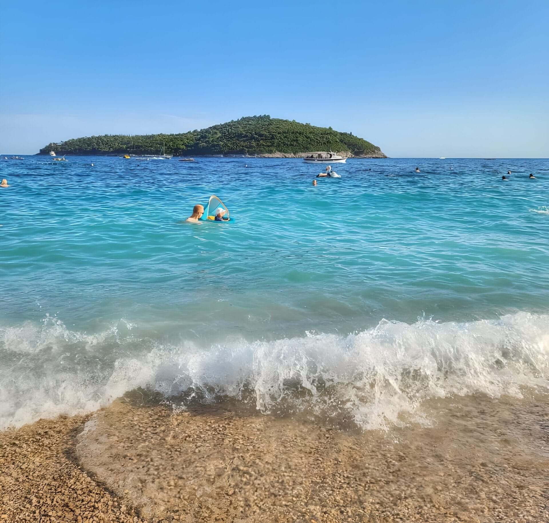 Beach near Old Town Dubrovnik People swimming and enjoying the clear blue waters of Plaza Banje in Dubrovnik, Croatia, with a scenic island visible in the background.