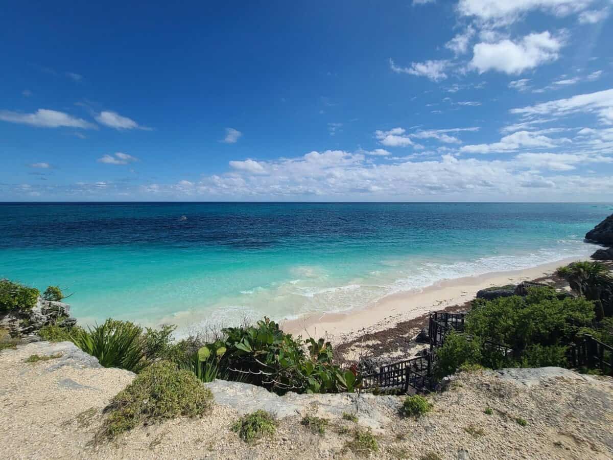 Scenic view of a pristine beach with turquoise waters and blue skies in Tulum, Mexico.