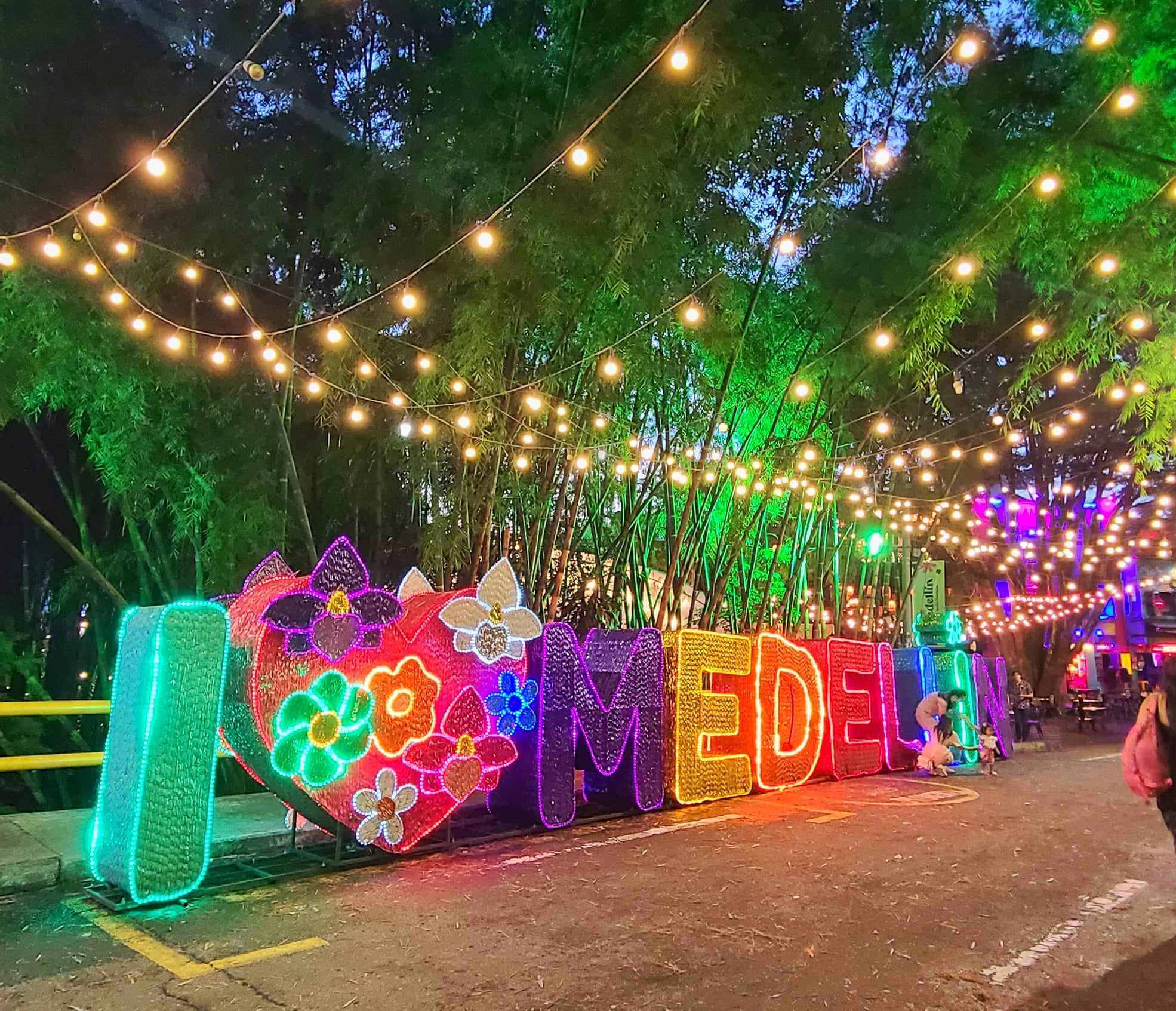 I Love Medellin sign illuminated at night in Medellin, Colombia, adorned with colorful lights and surrounded by string lights hanging above.