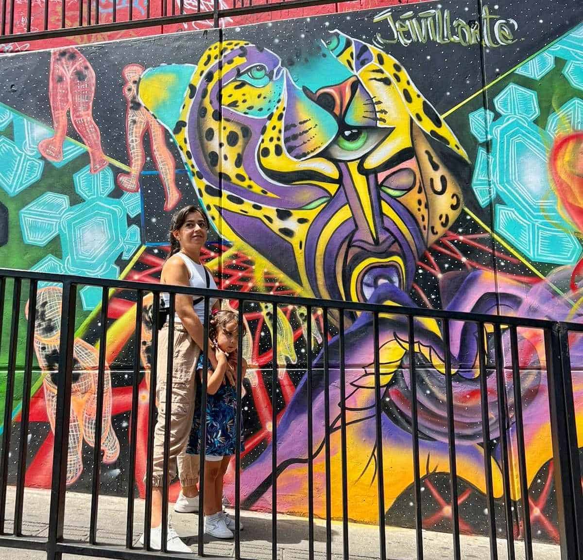 A woman and child standing in front of a colorful mural in Comuna 13, Medellin, Colombia.