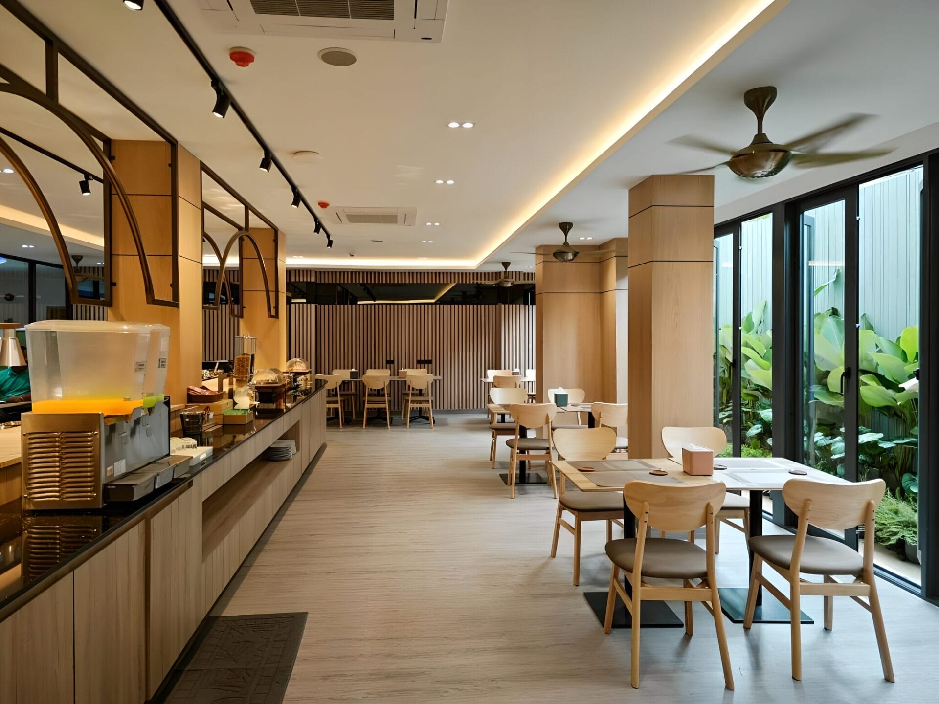 Modern dining area at Hi Chiangrai Hotel in Chiang Rai, Thailand, featuring wooden furniture and large windows.