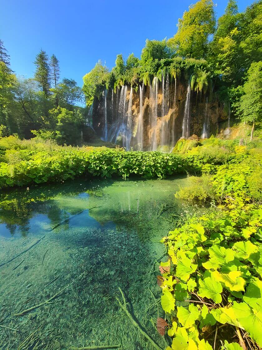 Plitvice National Park - Travel Croatia with toddler Waterfall cascading into a clear pool surrounded by lush greenery at Plitvice, Croatia.