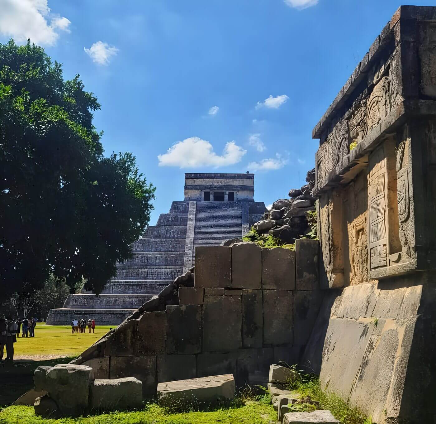 Ancient Mayan pyramid of Kukulcán, also known as El Castillo, in the background with ruins and carvings at Chichen Itza, Yucatan, Mexico, with a clear blue sky.