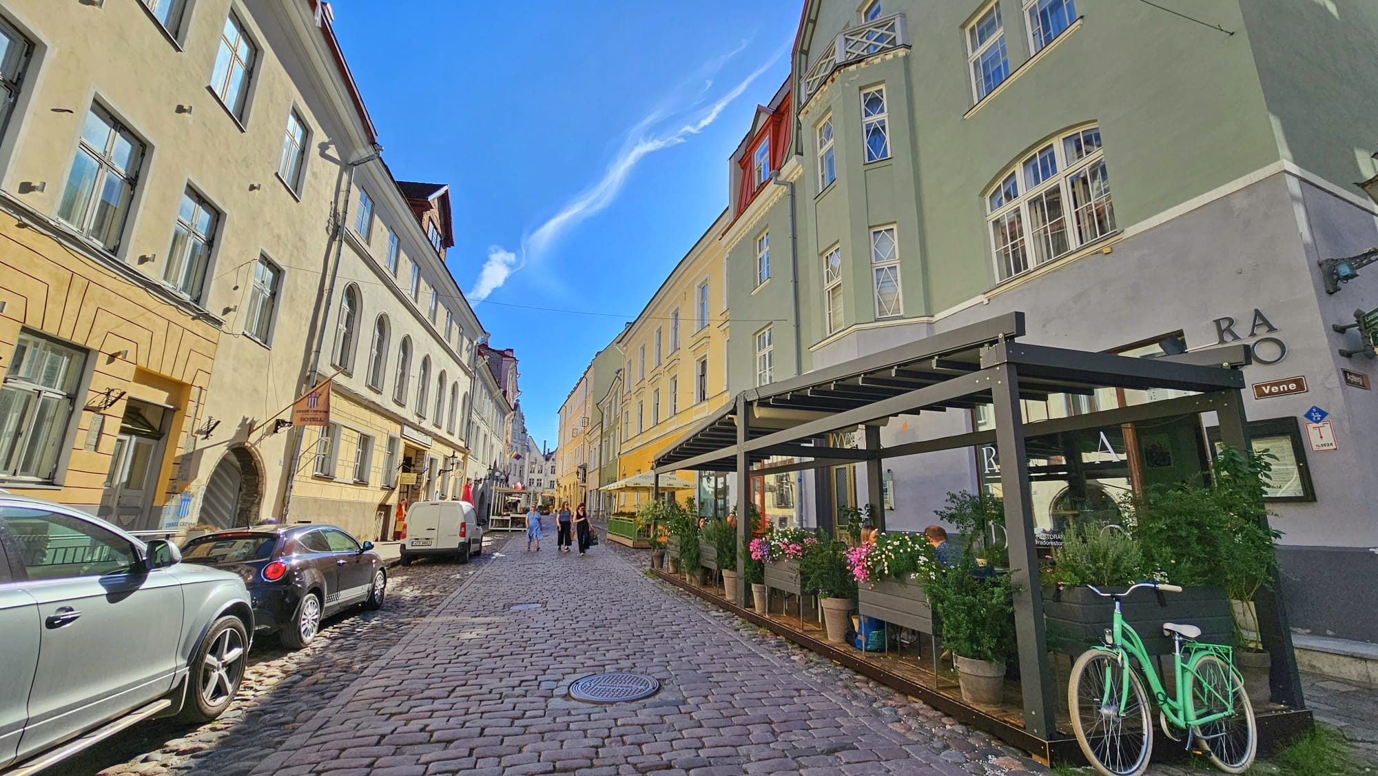 Cobblestone street with colorful buildings and outdoor restaurant seating in Tallinn, Estonia.