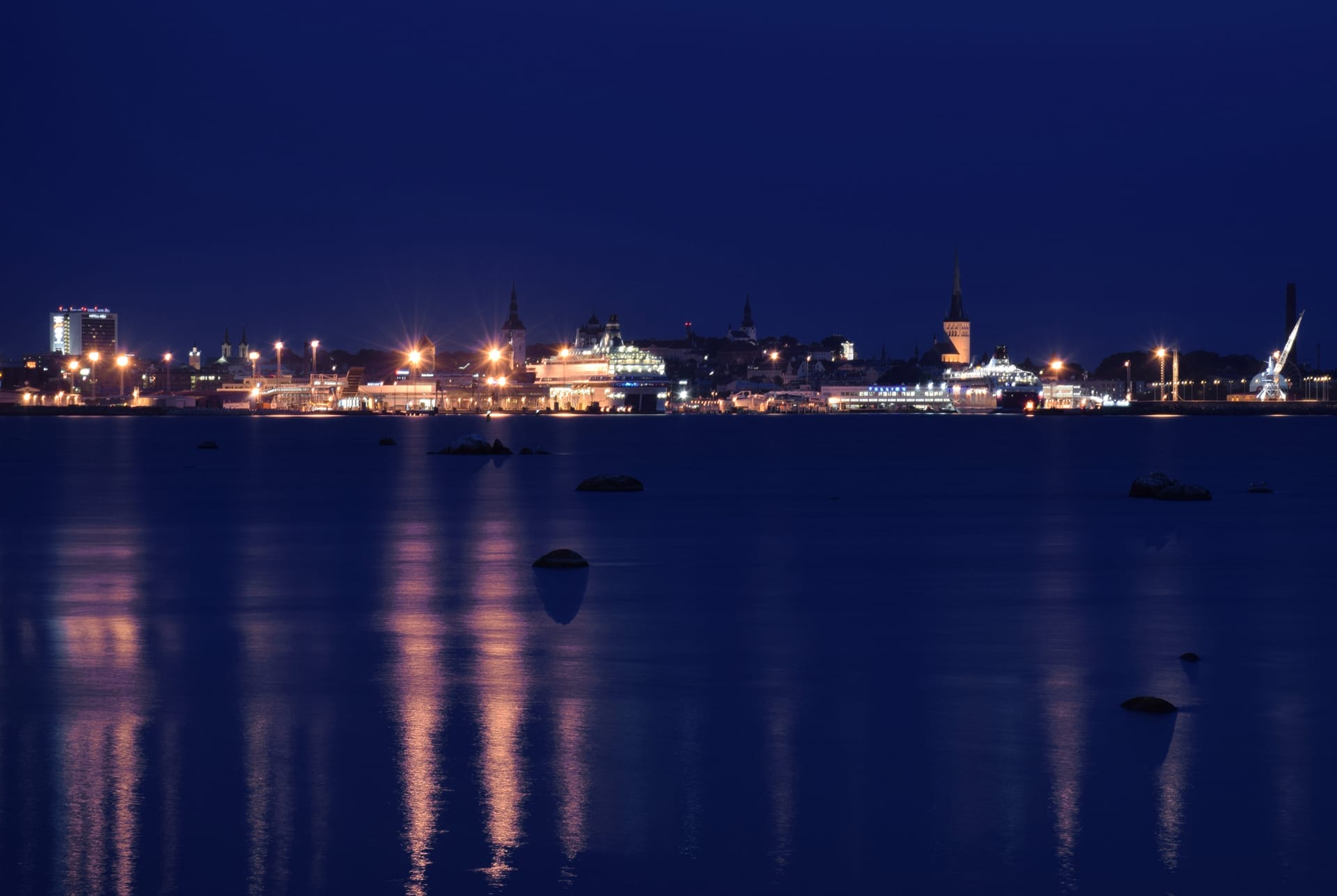 Night view of Tallinn, Estonia with city lights reflecting on the water.