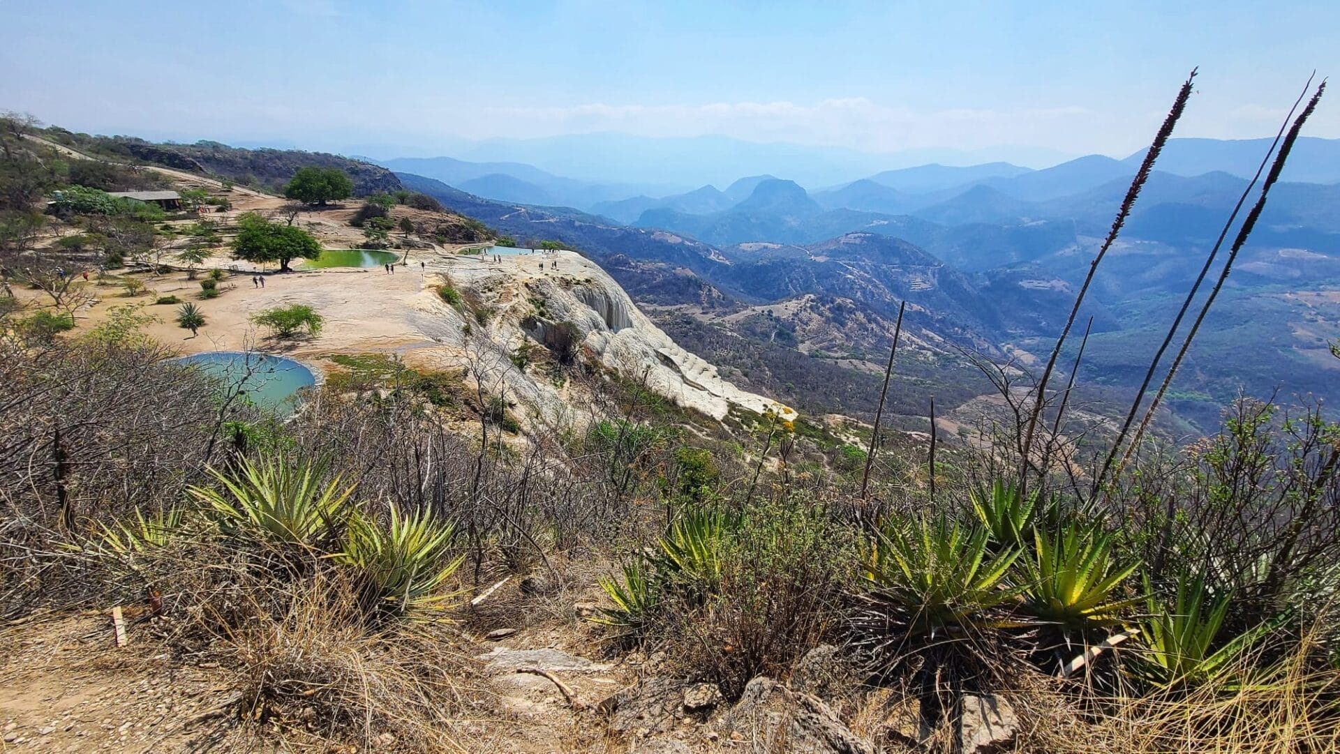 A scenic view of Hierve el Agua in Oaxaca, Mexico, featuring natural rock formations, mineral springs, and lush mountain landscape in the background.