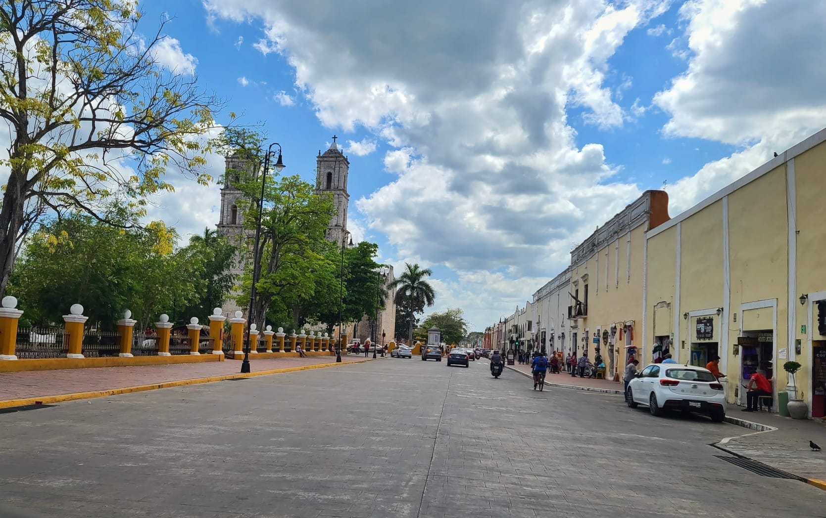 Street view of Valladolid, Mexico, with a historic church and colonial buildings under a partly cloudy sky.