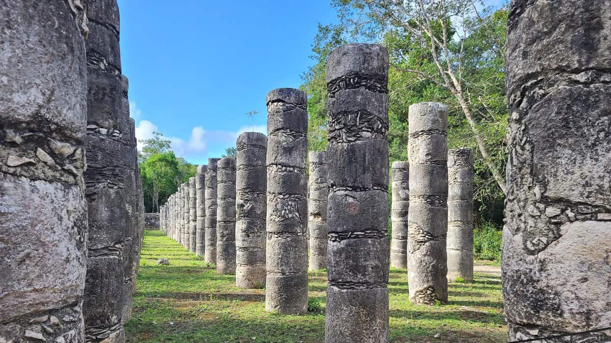 Rows of ancient stone columns at Chichen Itza, Yucatan, Mexico, under a clear blue sky.