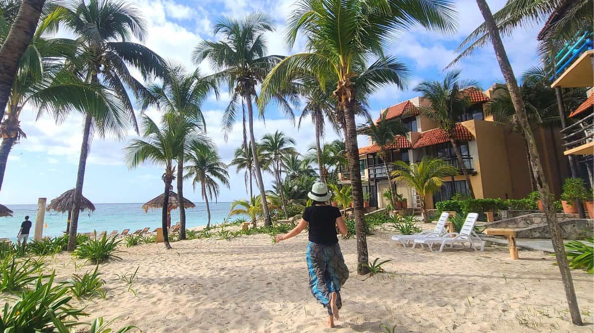A person walking towards the beachfront surrounded by palm trees at a resort in Akumal, Quintana Roo, Mexico.