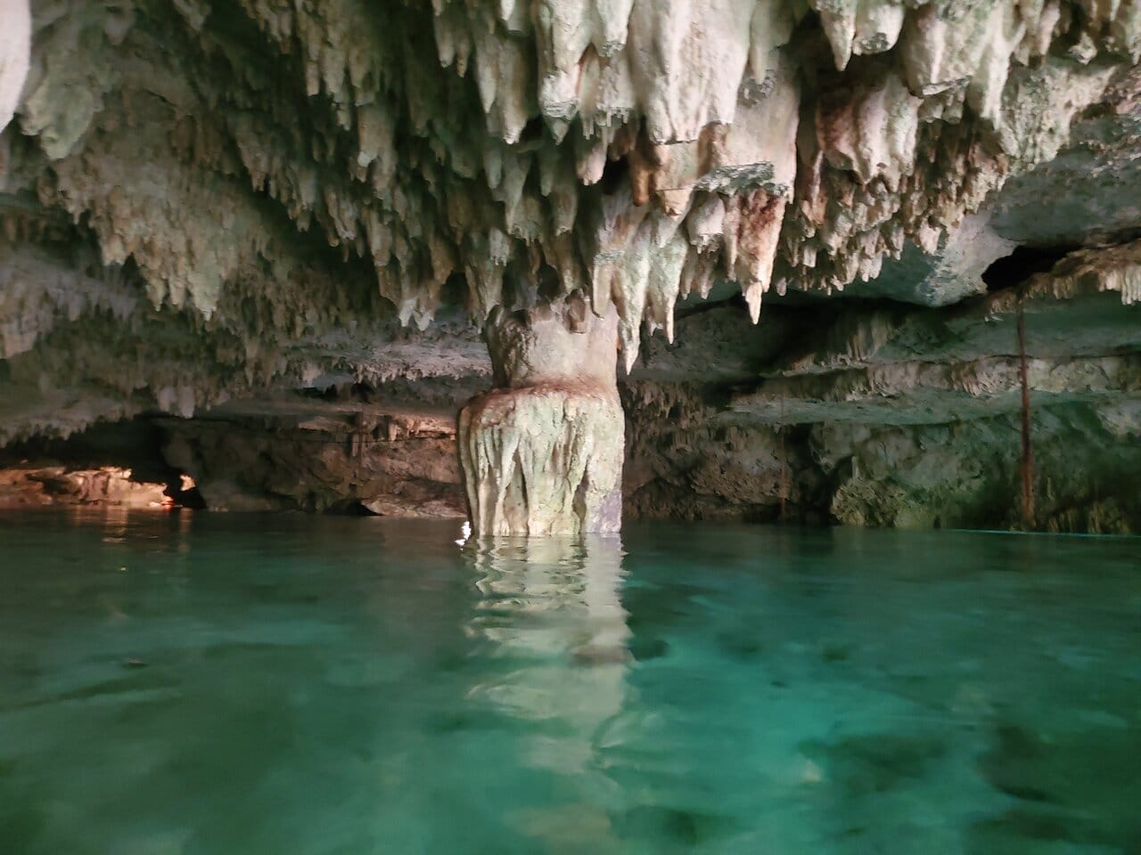 Underground cave formations with stalactites and stalagmites reflected in the clear waters of Yal Ku Lagoon in Akumal, Quintana Roo, Mexico.
