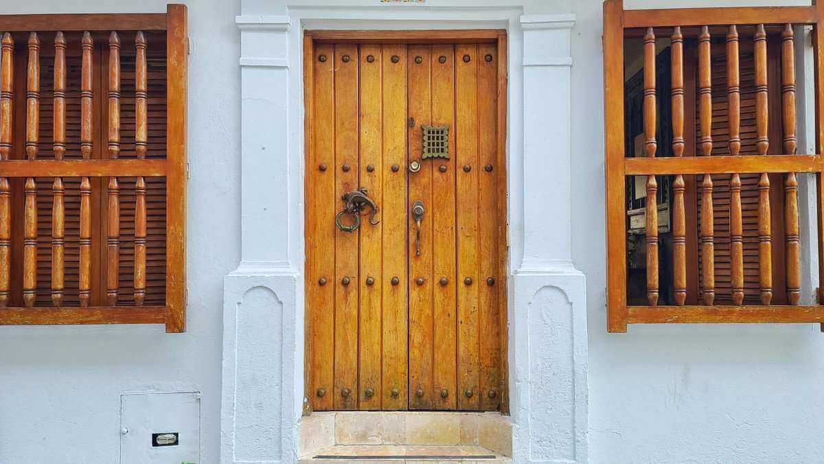 Traditional wooden door in Cartagena, Colombia, featuring a lizard-shaped door knocker.