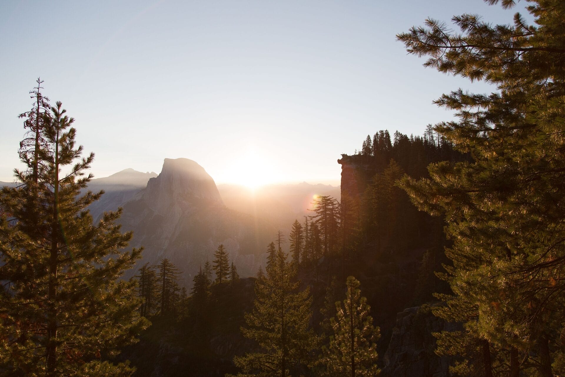 Sunset view from Glacier Point in Yosemite National Park, with Half Dome in the distance and trees silhouetted against the fading light.